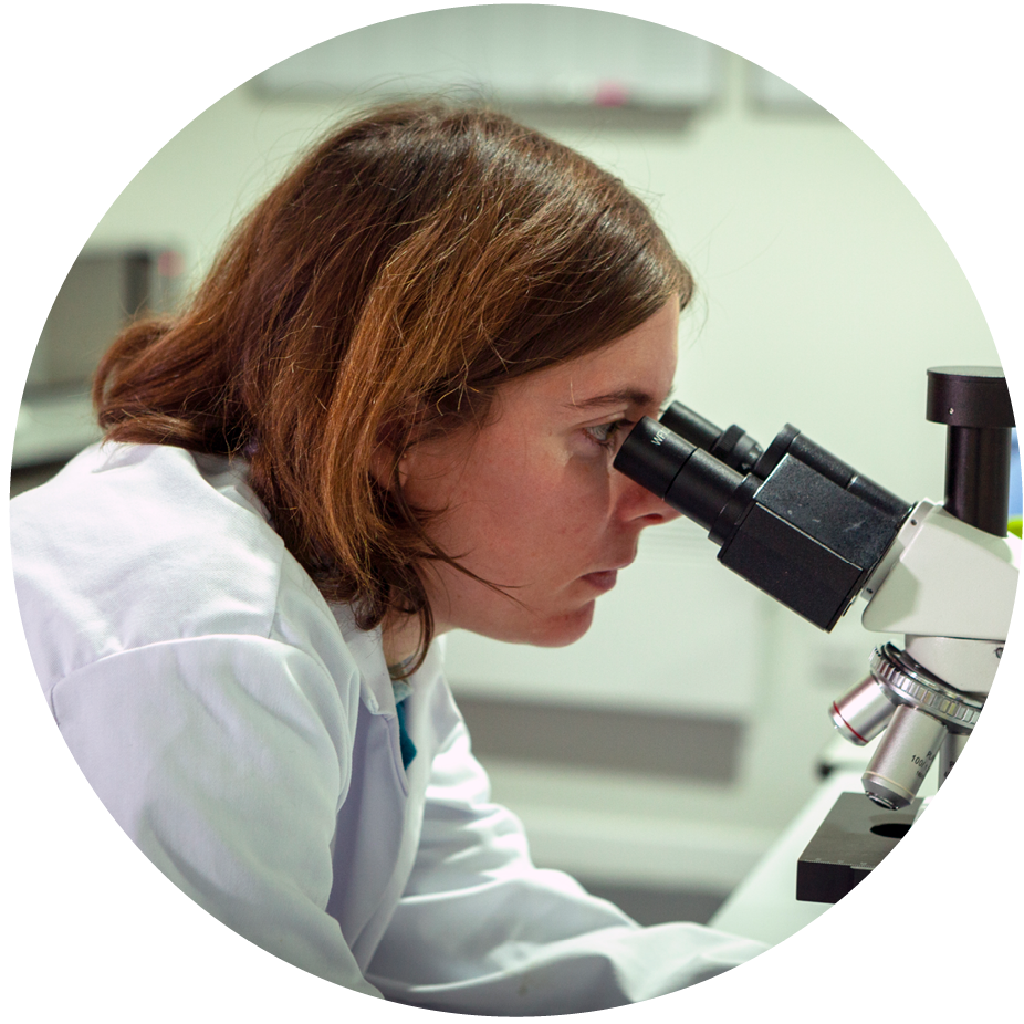 Women lab technician looking into microscope