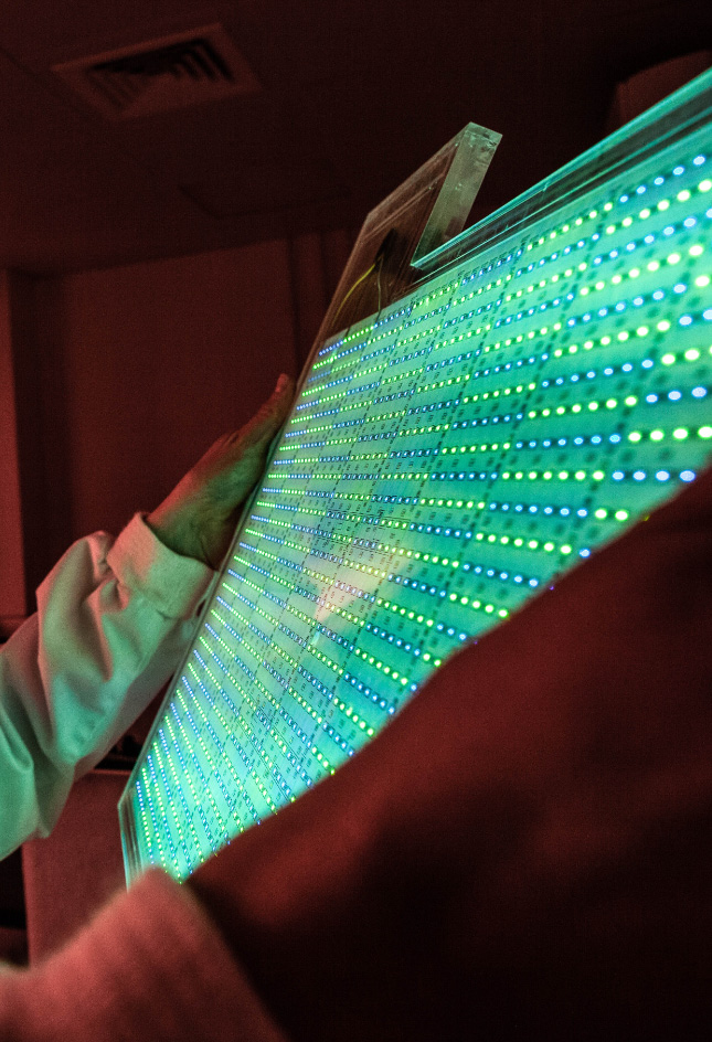 Glowing green/blue panel held by a pair of hands