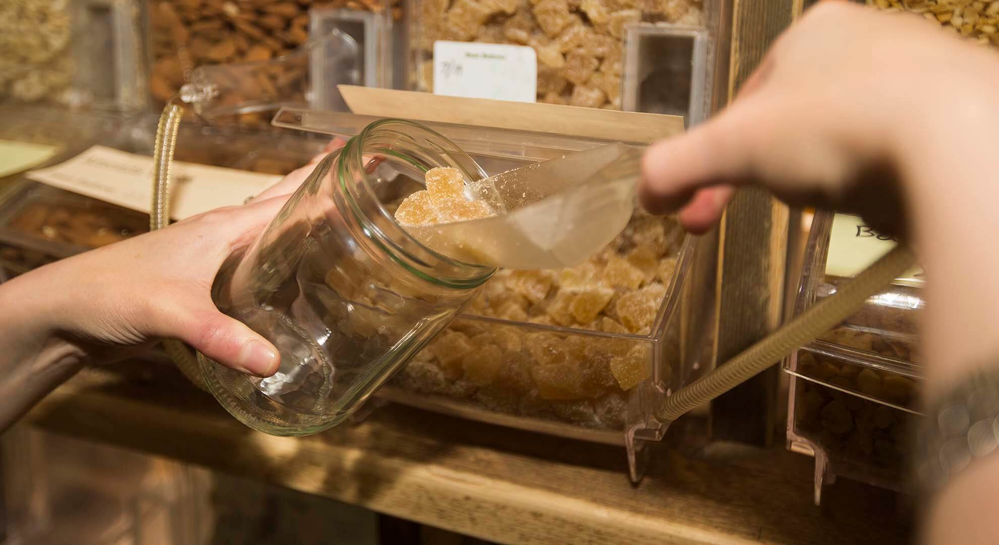 Person filling up a reusable jar at a zero waste refill store.jpeg