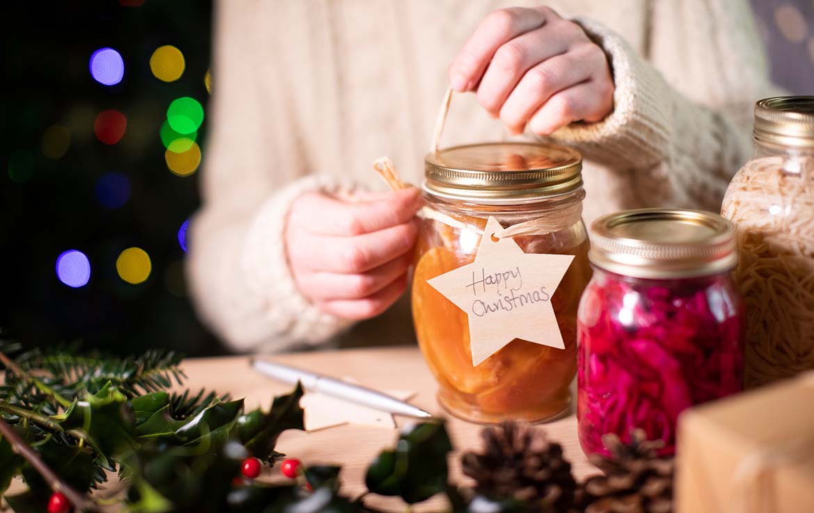 Person tying a gift tag to a jar of preserves - homemade Christmas presents