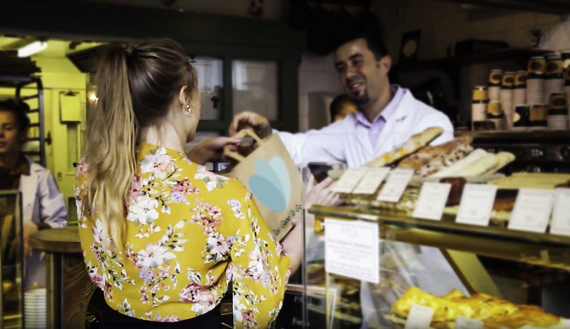 Woman collecting a Too Good To Go bag from a cafe counter
