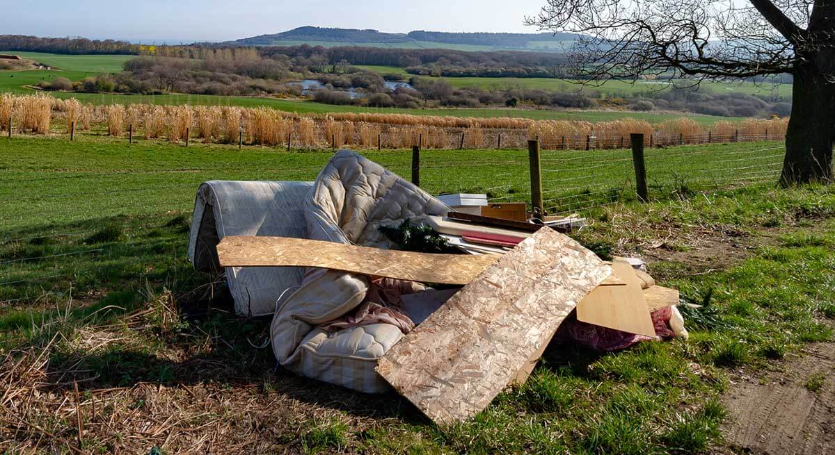 Image of a mattress which has been flytipped on grass in a rural area
