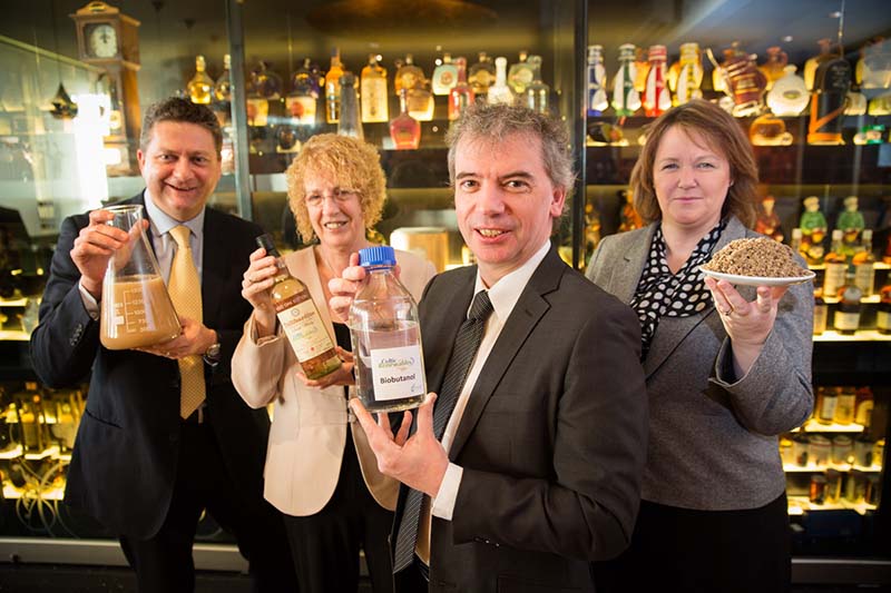 Photo of a group of people standing in front of bottles of spirits