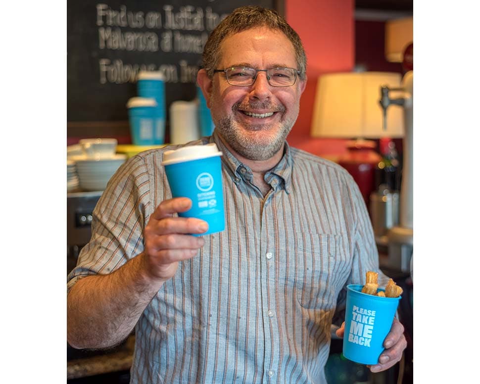 Photo of a man holding resusable coffee cups in a restaurant