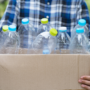 A person holding a box with clear plastic bottles ready to be recycled