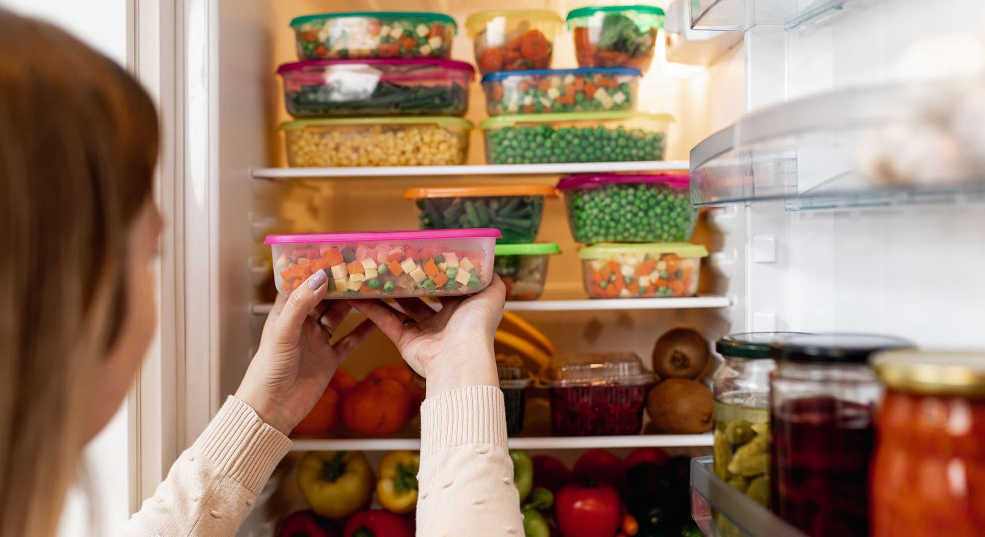 A person putting well stored food into a fridge