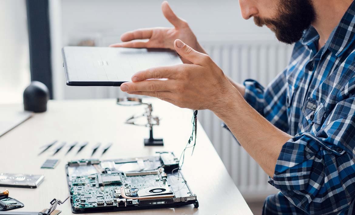 Photo of a person taking an electronic device apart to repair it