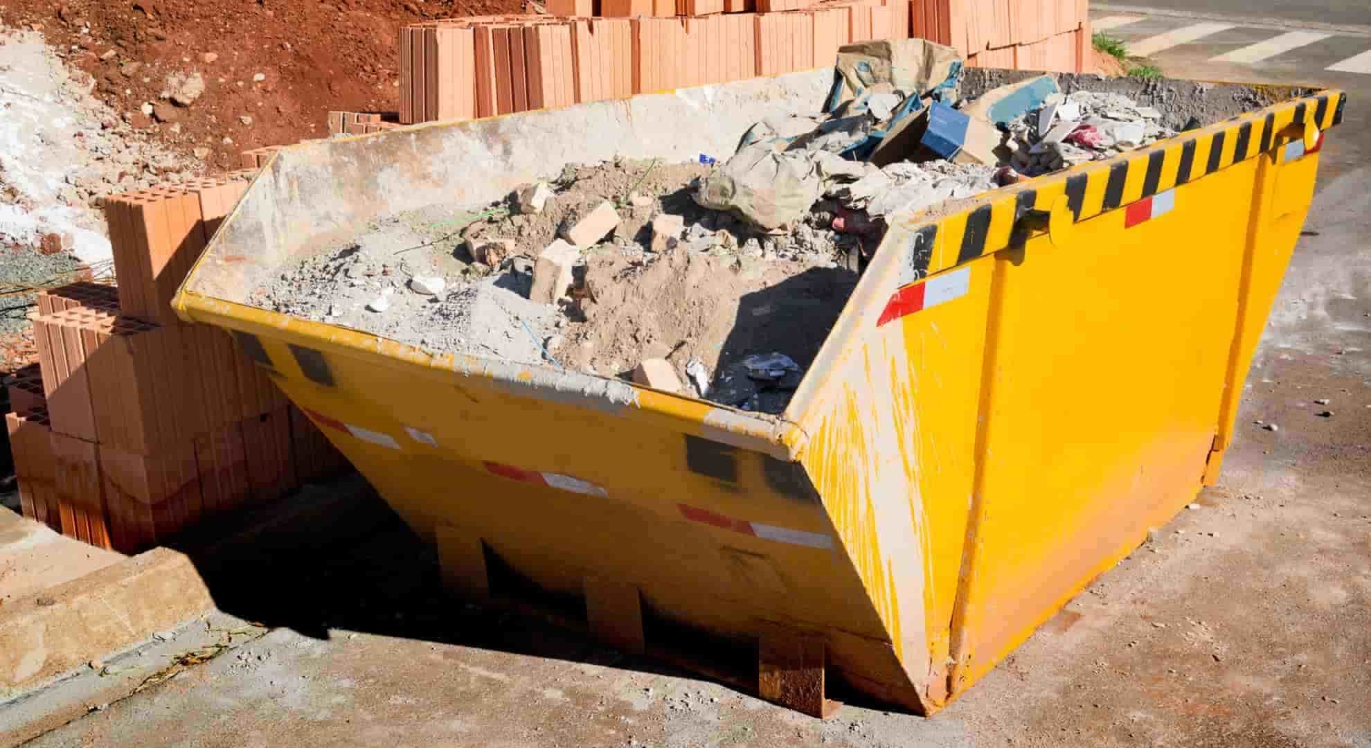 Photo of an yellow rubbish container at a construction site