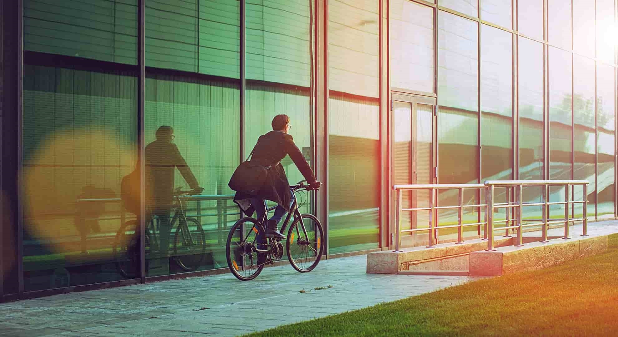 man riding bicycle beside the modern office building