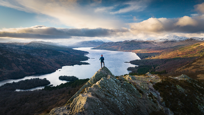 Man standing on scottish mountain with loch view