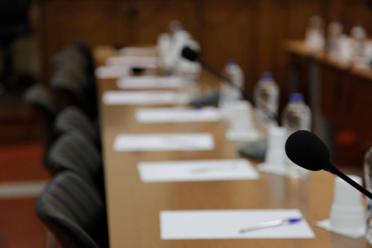 A board room set up with microphones on desks for a conference