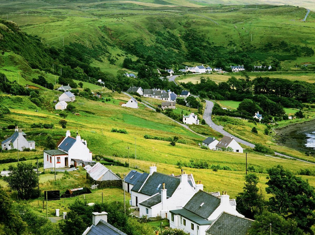 A green countryside landscape featuring small white cottages